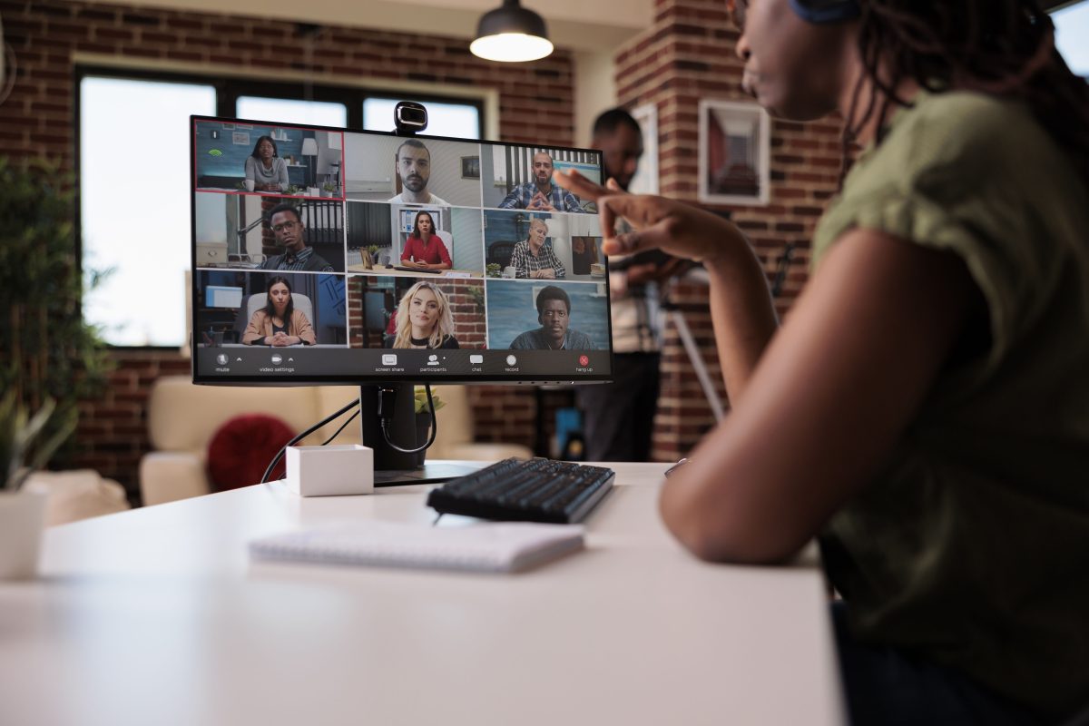 Selective focus computer screen with startup team startup employees working remote group video call brainstorming ideas african american woman gesturing internet meeting with colleagues copy