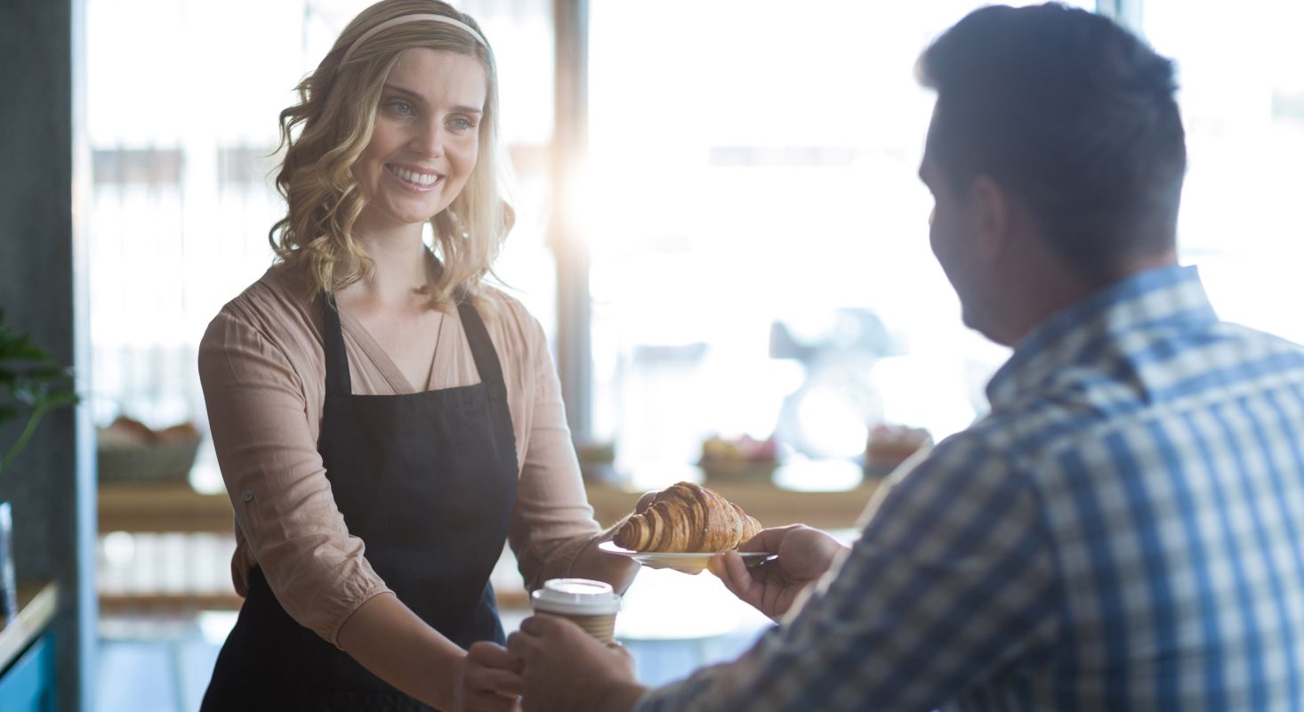 Waitress serving cup coffee croissant customer