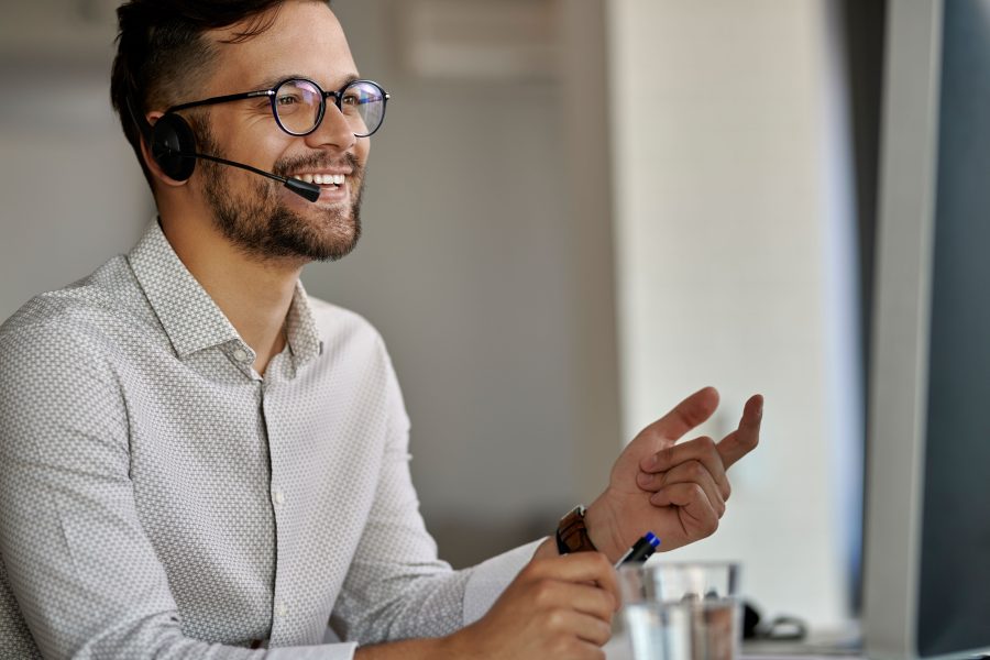 Happy call center agent using computer while communicating with clients working office