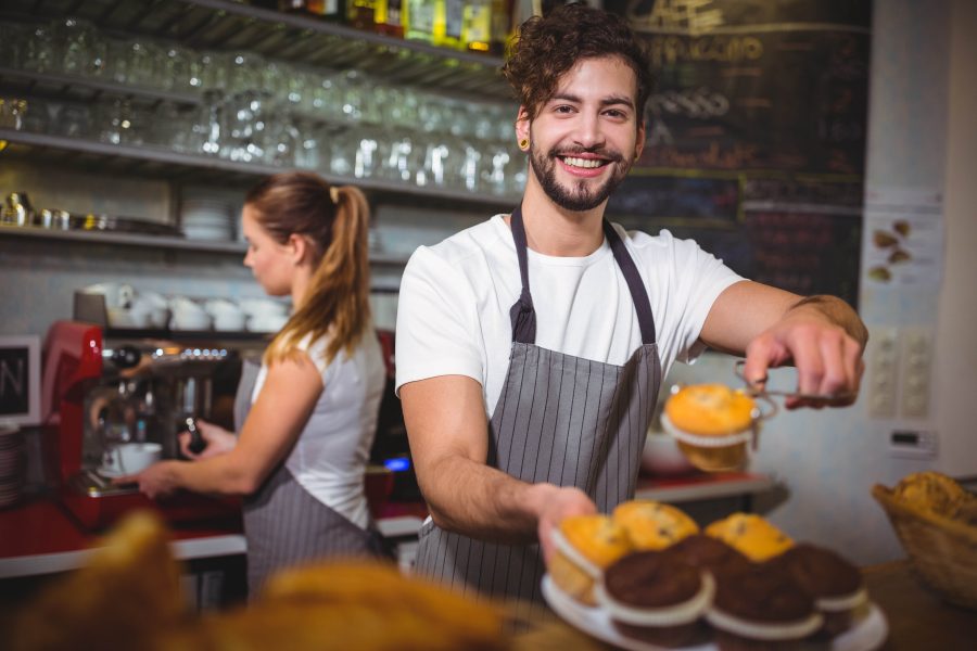 Portrait waiter holding plate cup cake counter