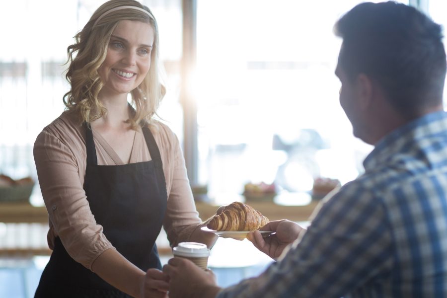 Waitress serving cup coffee croissant customer