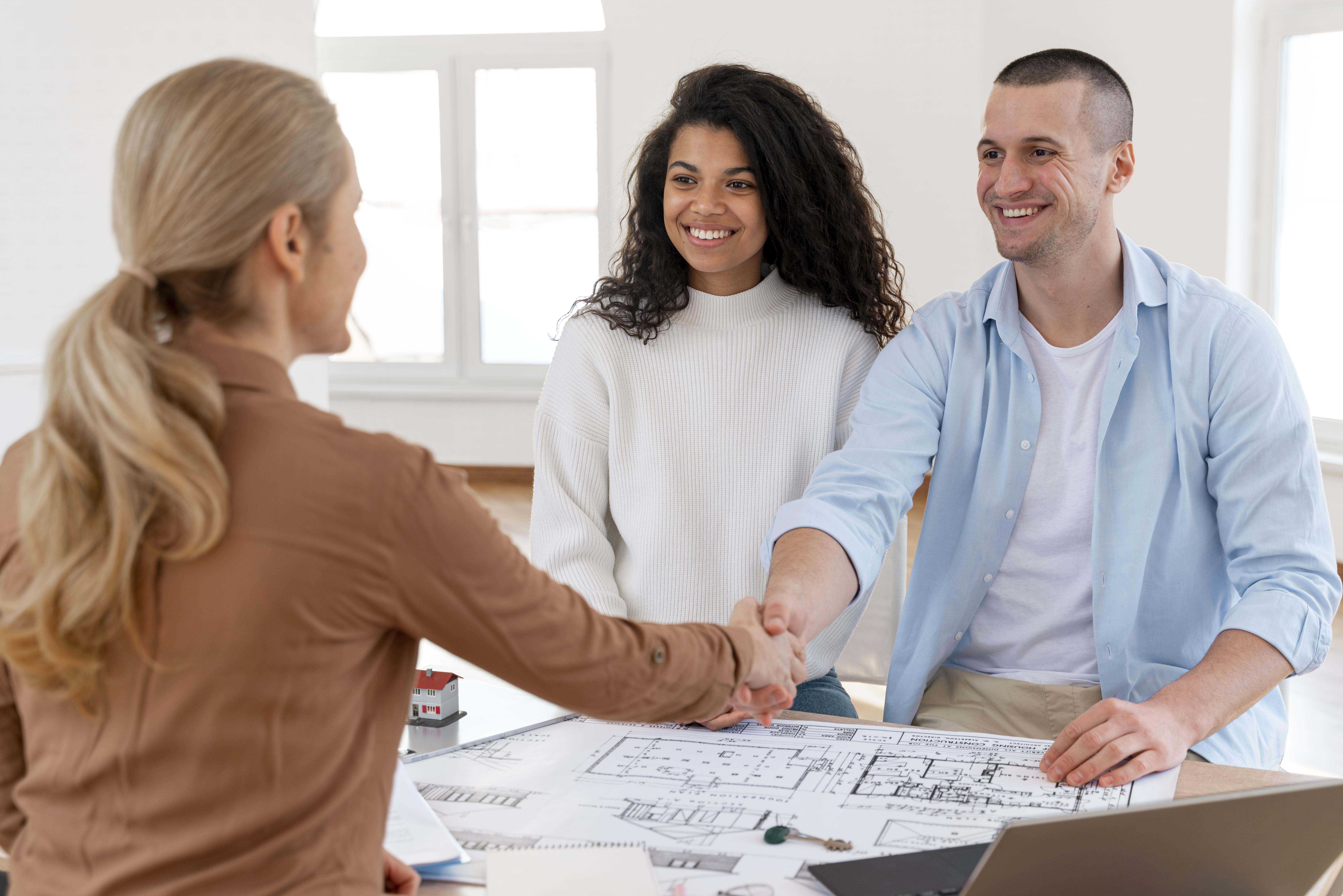 Female realtor handshaking couple congratulate them their new house copy