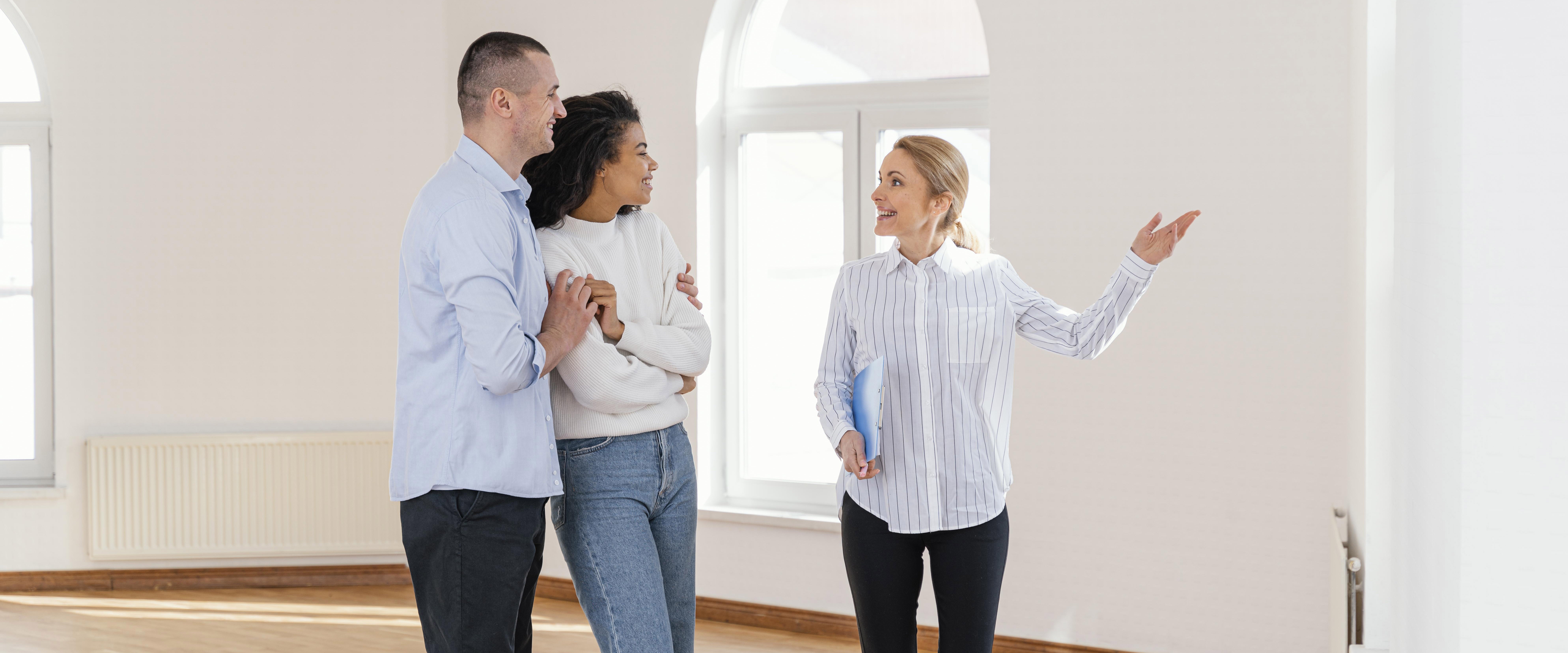 Smiley female realtor showing empty house couple copy