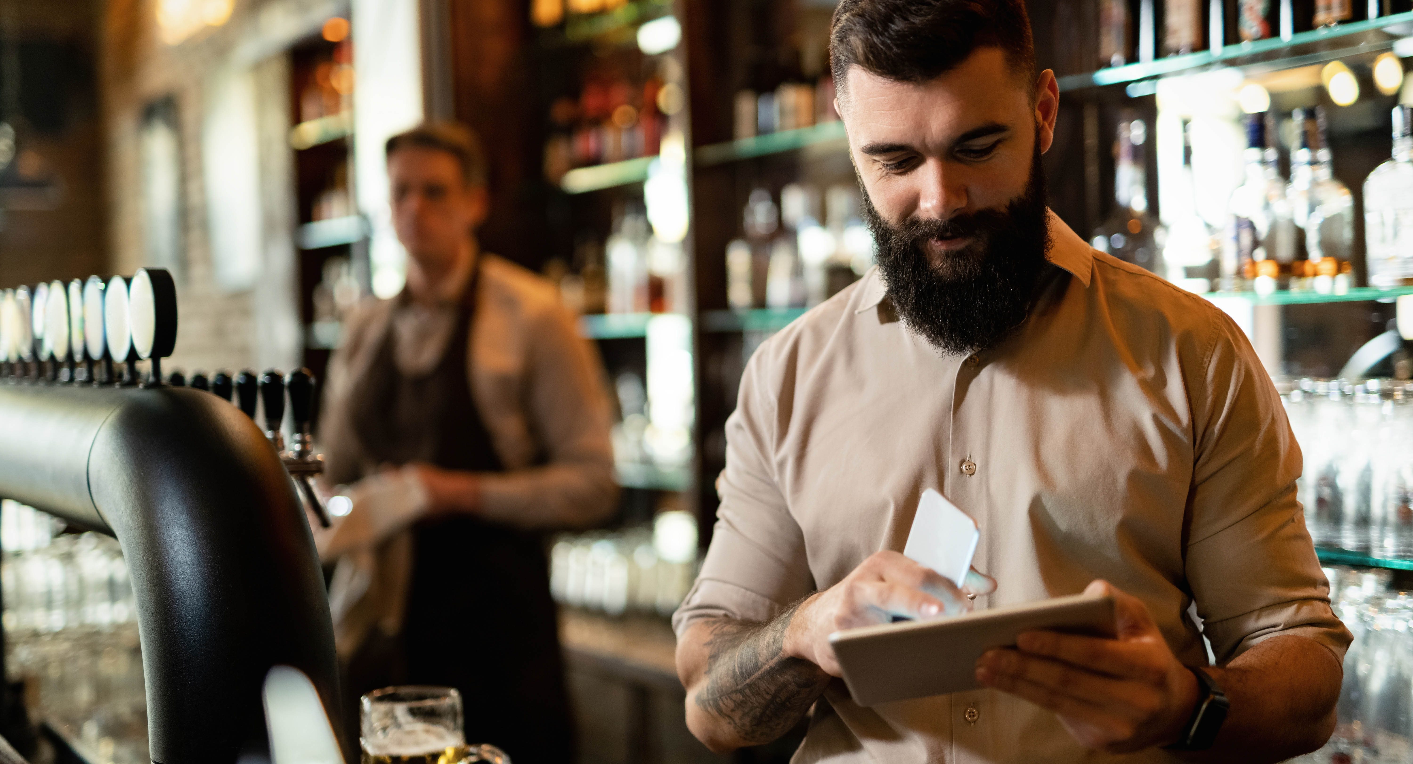 Young happy barista working bar surfing net touchpad